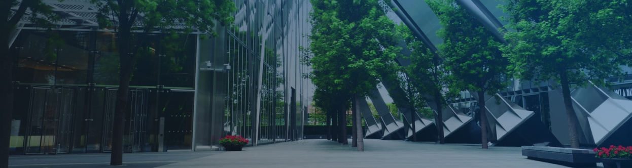 View of glass office buildings surrounded by trees, overlaid with a blue gradientt